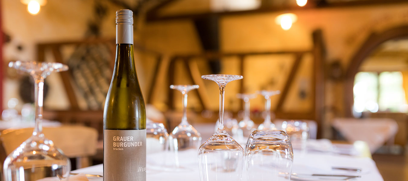 Atmosphärisches Foto eines Tisches mit einer Weinflasche und Gläsern aus dem Restaurant des Weinguts Weber. 