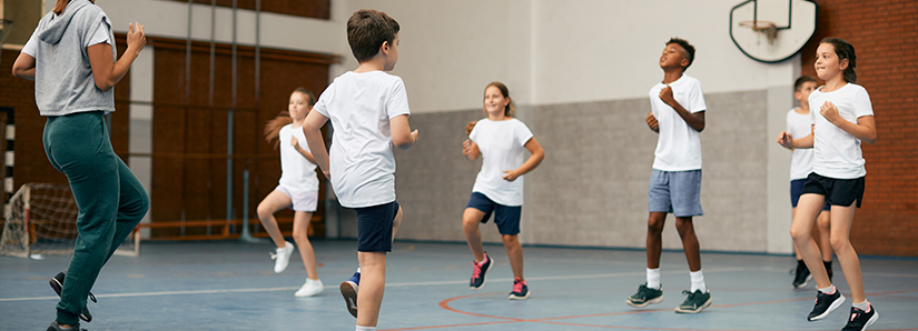 Schulkinder trainieren im Sportunterricht in einer Schulsporthalle.
