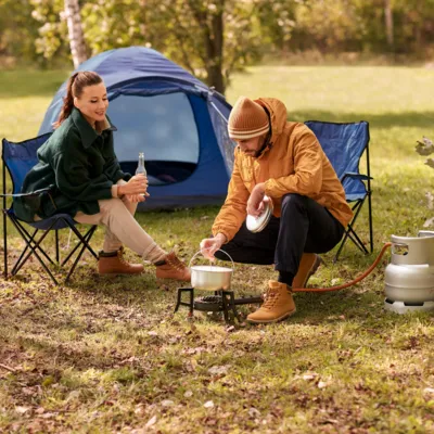 Campingkocher mit Gasflasche vor einem Zelt