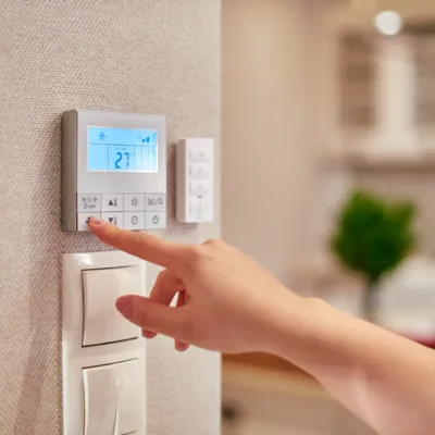 Energiesparen: Person bedient Wandthermostat der Heizung