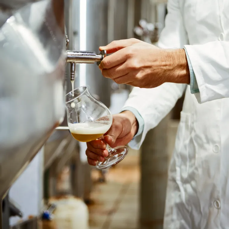 Ein Mitarbeiter der Brauerei Lübz beim Einschenken eines Glases Bier.